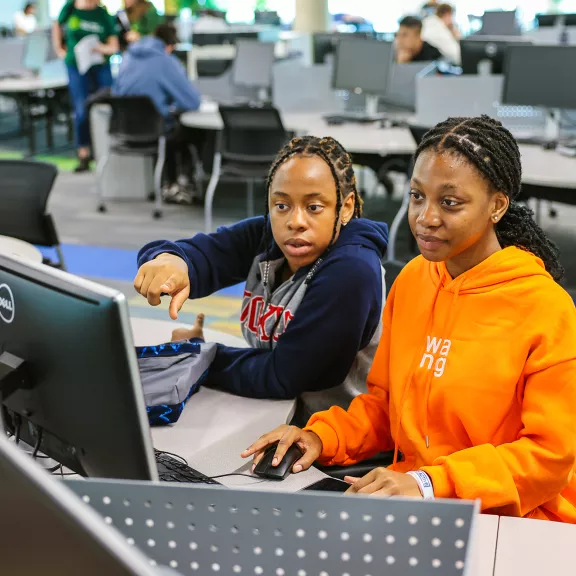 two students collaborating on computer in library