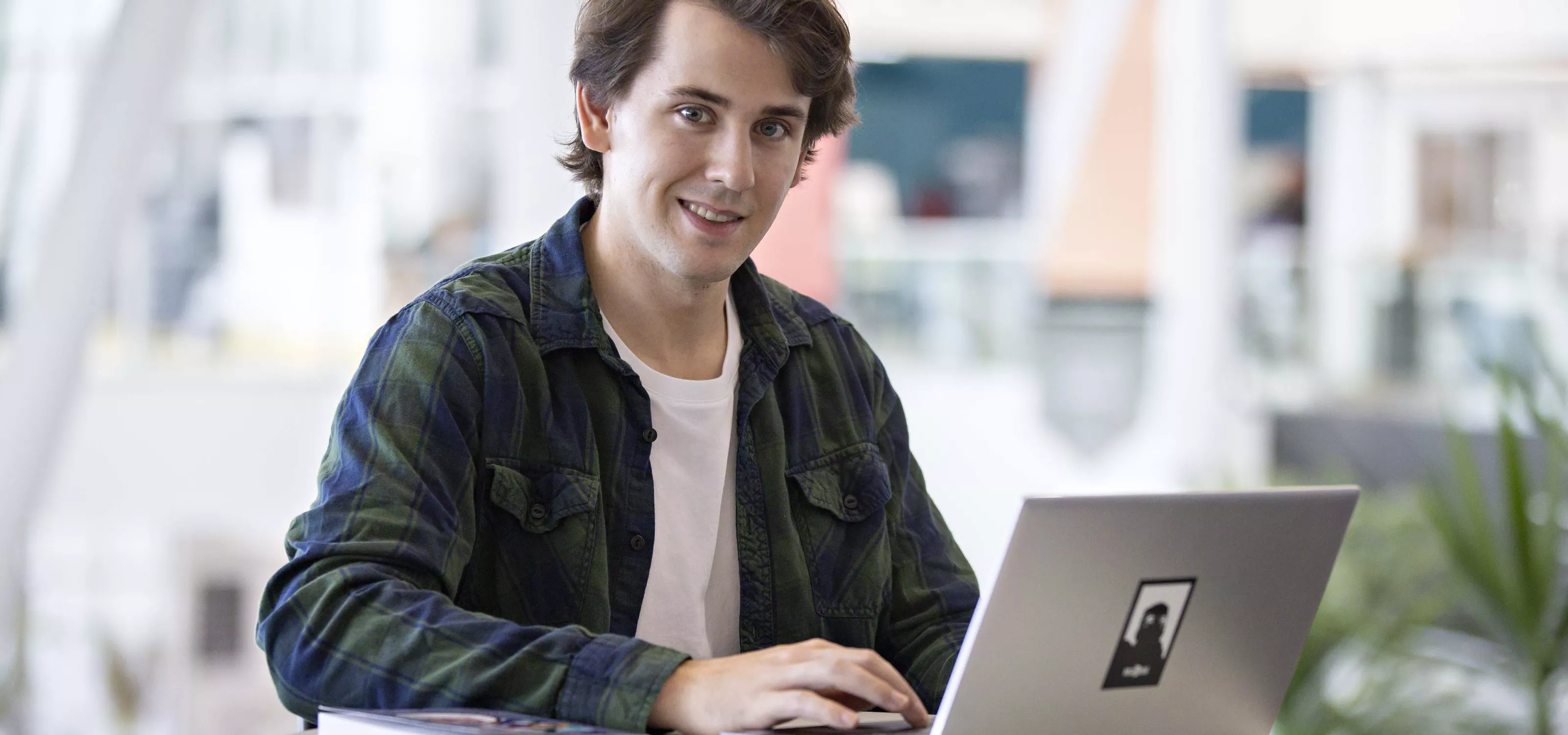 Young man with open laptop looking at the camera.