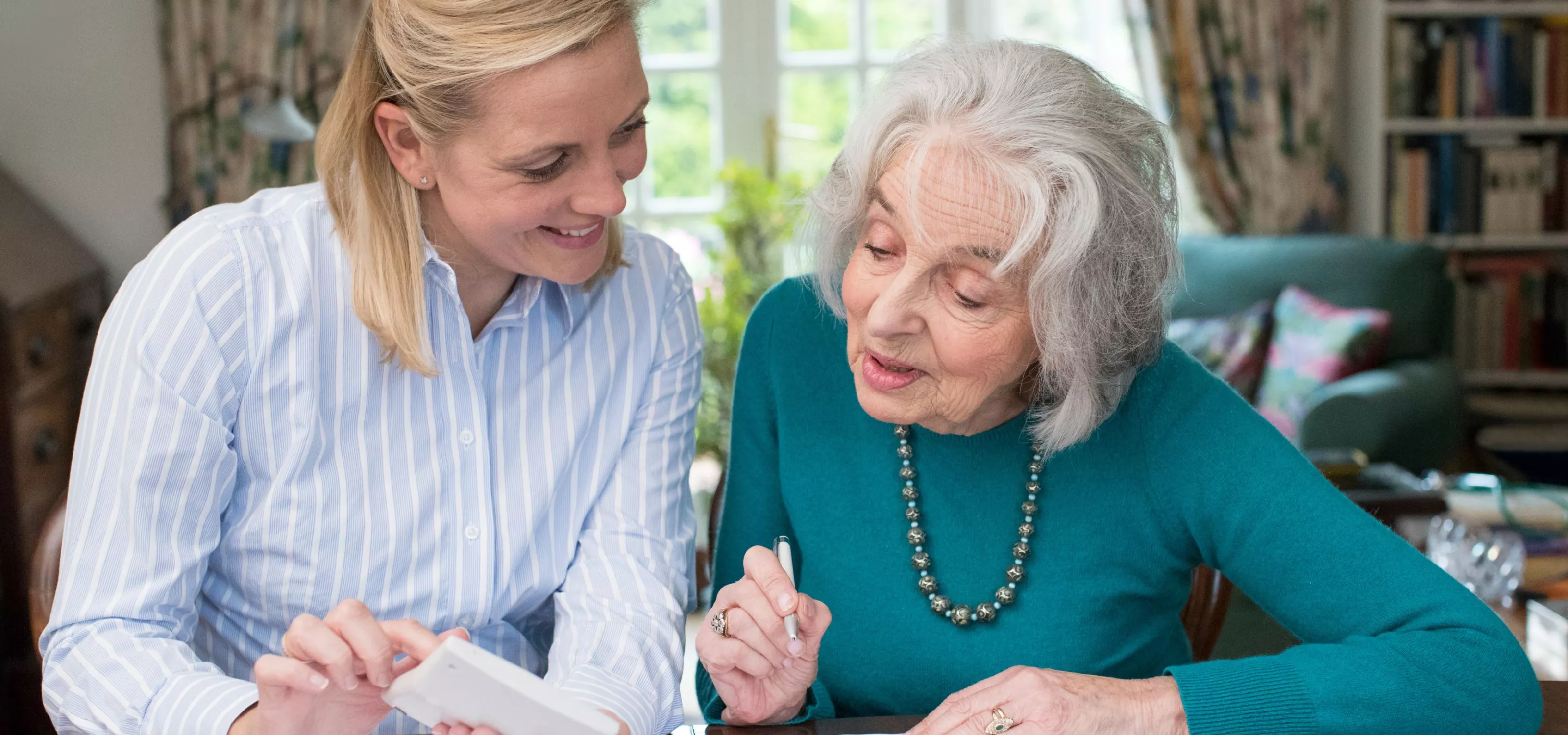 One woman helping another elderly woman with financial planning.
